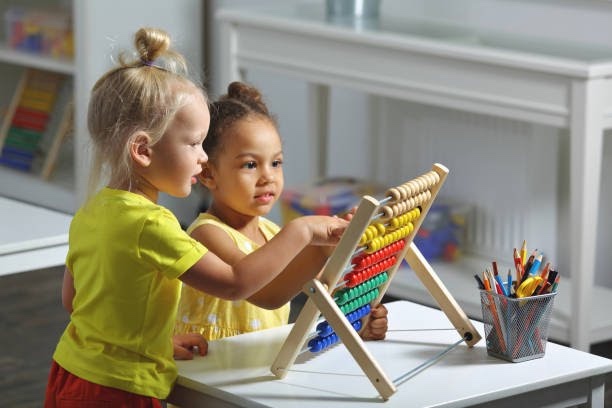 Two preschool children learning together with a colorful abacus