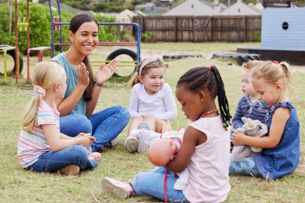A childcare teacher supervising young children playing outdoors